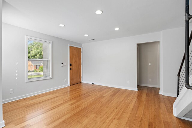 spare room with stairs, light wood-style flooring, recessed lighting, and baseboards
