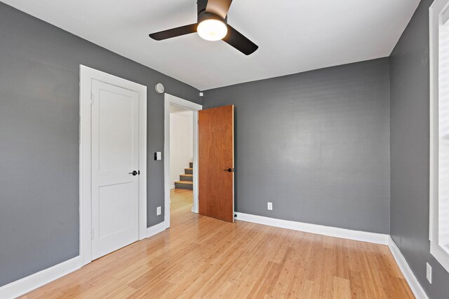 unfurnished bedroom with light wood finished floors, baseboards, and a ceiling fan