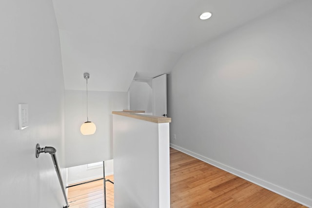 stairway with wood finished floors, vaulted ceiling, and baseboards