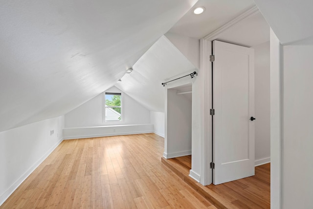 additional living space featuring light wood-style floors, baseboards, lofted ceiling, and recessed lighting
