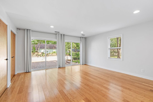 unfurnished room with healthy amount of natural light, light wood-type flooring, recessed lighting, and baseboards
