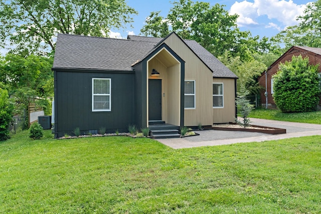 view of front of property featuring a shingled roof, central AC, and a front yard