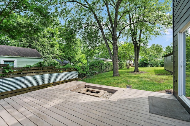 deck featuring a fire pit, a lawn, and view of scattered trees