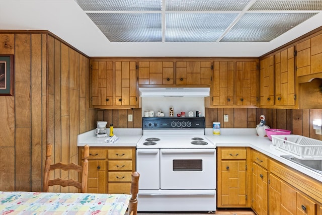 1326 Holly Tree Gap Rd, Brentwood, TN 37027 - kitchen featuring electric stove, under cabinet range hood, wood walls, light countertops, and brown cabinets