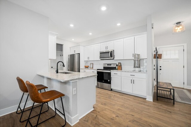 2617 Leawood Ct, Murfreesboro, TN 37128 - kitchen with stainless steel appliances, a sink, a kitchen bar, tasteful backsplash, and white cabinets
