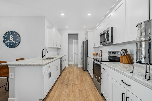 2617 Leawood Ct, Murfreesboro, TN 37128 - kitchen with appliances with stainless steel finishes, a sink, a kitchen bar, decorative backsplash, and recessed lighting