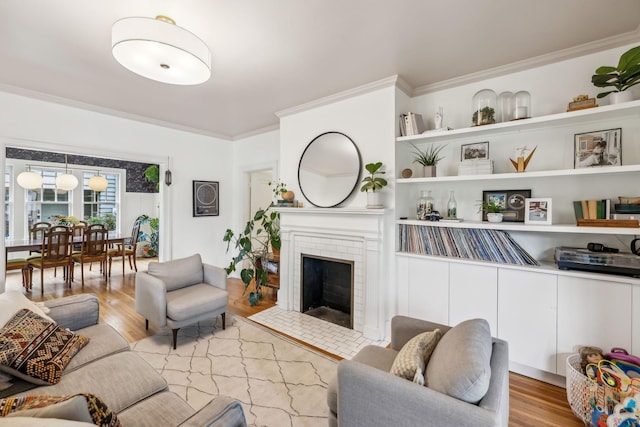 living area featuring ornamental molding, wood finished floors, and a fireplace