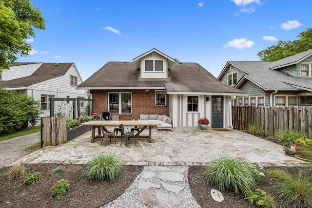 rear view of house featuring brick siding, a patio, an outdoor living space, fence, and roof with shingles
