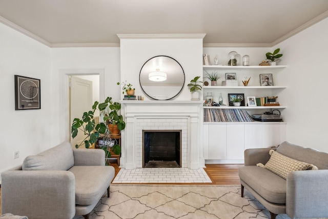 living area with crown molding, wood finished floors, and a fireplace