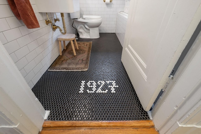 bathroom with toilet, tile walls, and tile patterned floors