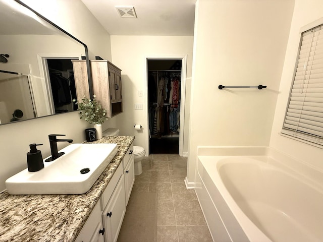 full bathroom featuring tile patterned flooring, a garden tub, vanity, and a spacious closet