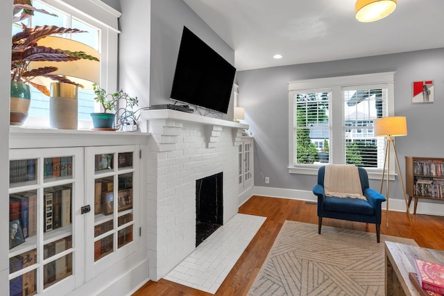 living room featuring a fireplace, wood finished floors, baseboards, and recessed lighting