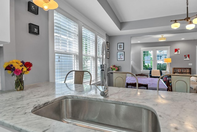 kitchen featuring light stone countertops, pendant lighting, and a sink
