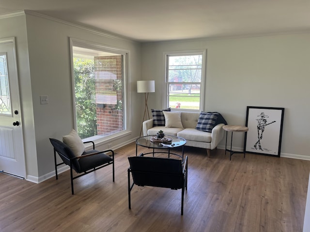 living area with crown molding, wood finished floors, and baseboards