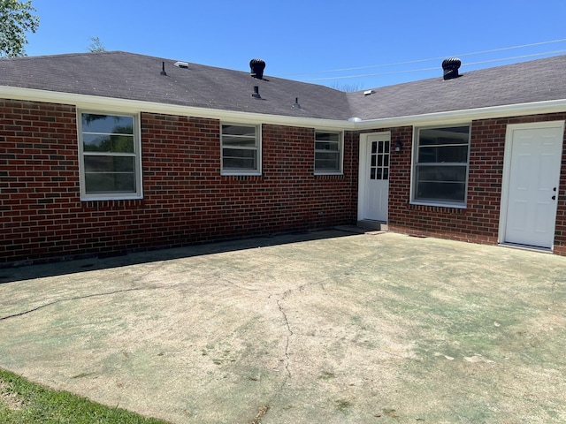 back of house featuring a patio, brick siding, and a shingled roof