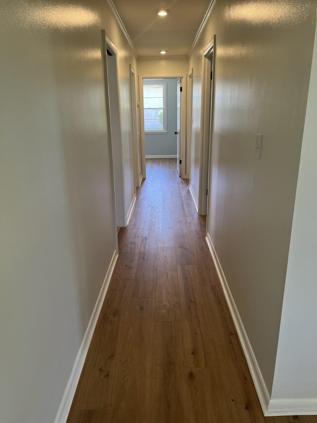 hallway featuring dark wood finished floors, ornamental molding, baseboards, and recessed lighting