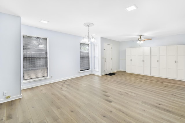 unfurnished living room with a ceiling fan, light wood finished floors, baseboards, and a chandelier