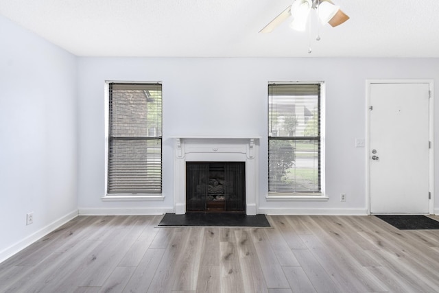 unfurnished living room with a fireplace with flush hearth, wood finished floors, ceiling fan, and baseboards