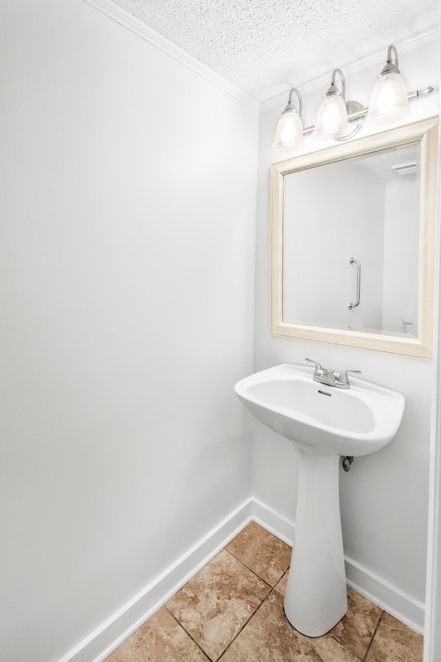 bathroom featuring tile patterned floors, ornamental molding, baseboards, and a textured ceiling