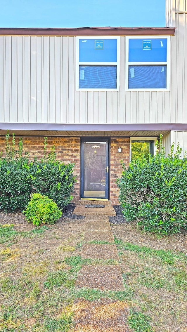 entrance to property featuring brick siding and board and batten siding