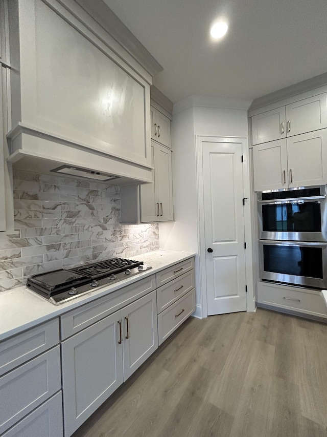 5742 Sagebrush Dr, Murfreesboro, TN 37129 - kitchen with double oven, light wood-style flooring, gas stovetop, decorative backsplash, and light countertops