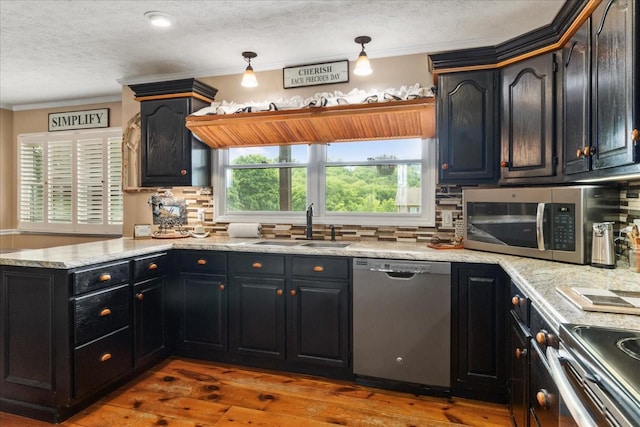 kitchen with appliances with stainless steel finishes, a sink, light countertops, backsplash, and hardwood / wood-style flooring