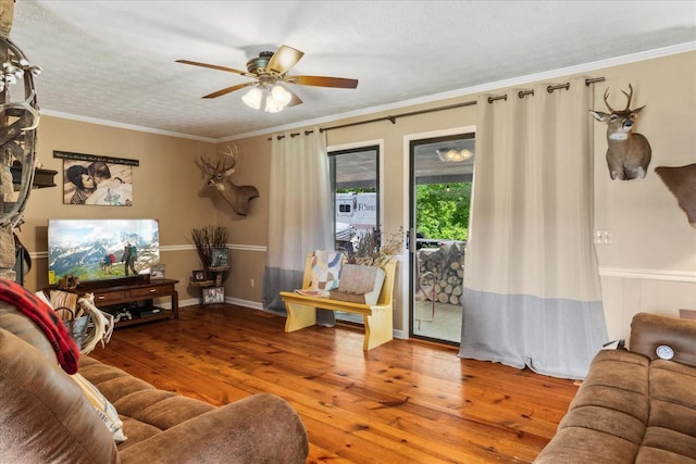 living area with a ceiling fan, hardwood / wood-style floors, and ornamental molding