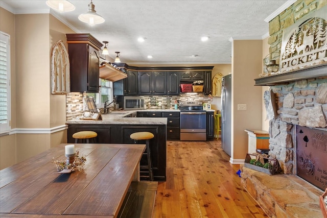 kitchen with stainless steel appliances, a peninsula, light wood-style floors, tasteful backsplash, and a sink