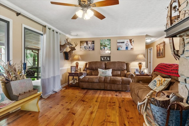 living area featuring crown molding, hardwood / wood-style flooring, a ceiling fan, and baseboards