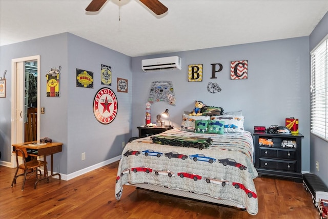 bedroom with an AC wall unit, wood finished floors, baseboards, and ceiling fan