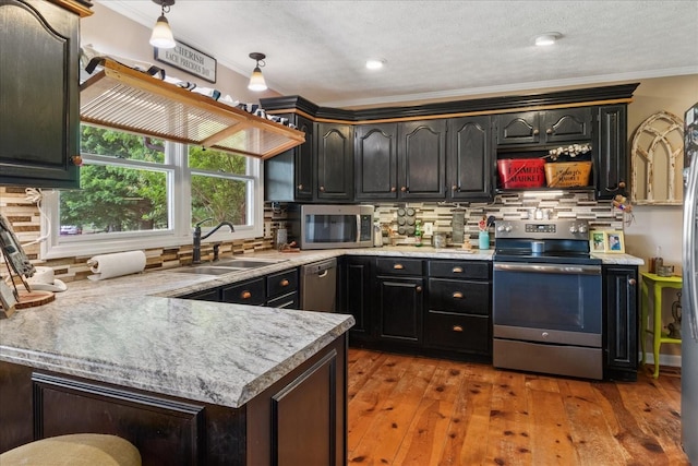 kitchen featuring appliances with stainless steel finishes, a sink, ornamental molding, decorative backsplash, and light countertops