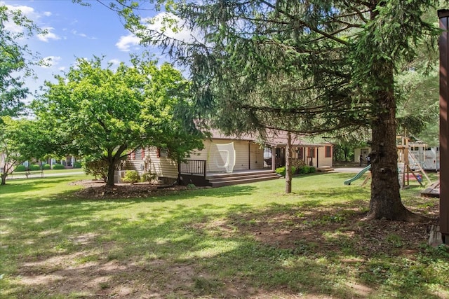 view of grassy yard featuring a playground and a deck
