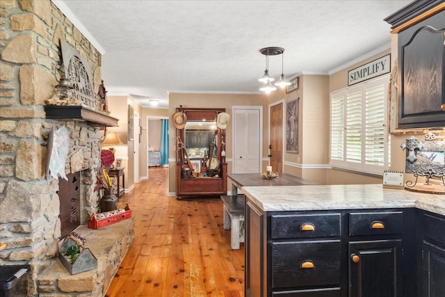 kitchen with a textured ceiling, light wood-type flooring, light countertops, a peninsula, and ornamental molding