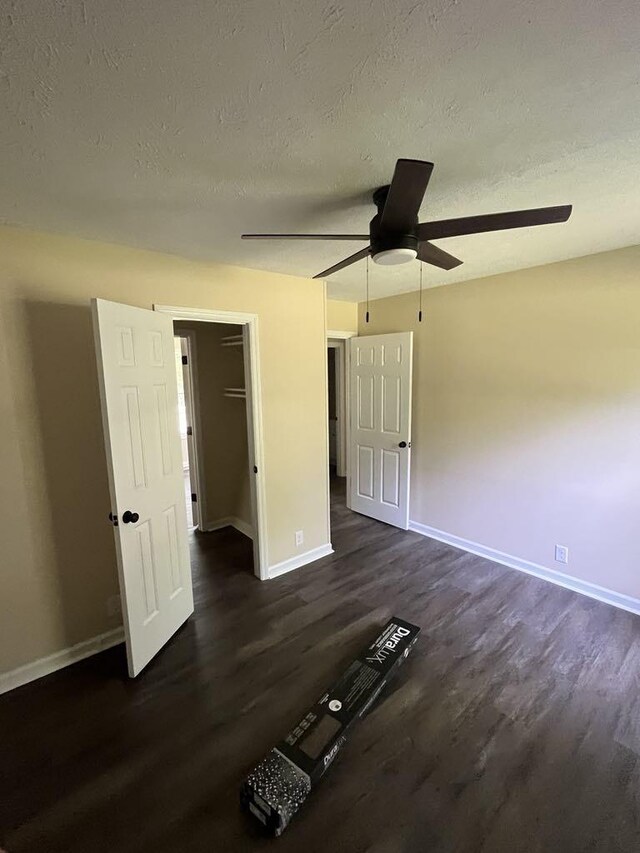 8315 Oak Springs Rd, Nunnelly, TN 37137 - unfurnished bedroom featuring dark wood-style flooring, baseboards, a textured ceiling, and a ceiling fan