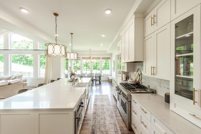 kitchen with high end stainless steel range oven, a large island, dark wood-type flooring, white cabinets, and decorative backsplash