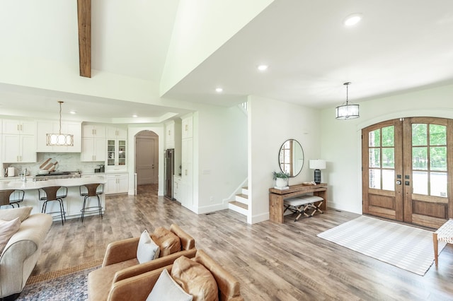 living area with arched walkways, french doors, recessed lighting, stairs, and light wood-style floors