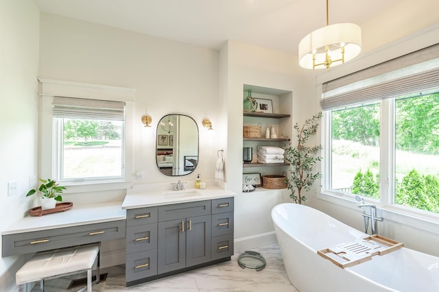 bathroom featuring healthy amount of natural light, a freestanding bath, and marble finish floors