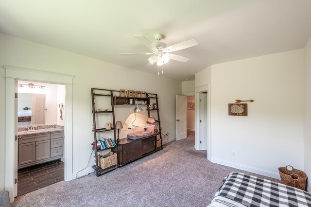 bedroom featuring dark colored carpet, baseboards, connected bathroom, a sink, and ceiling fan