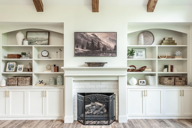 living area with beamed ceiling, light wood-style floors, and a fireplace