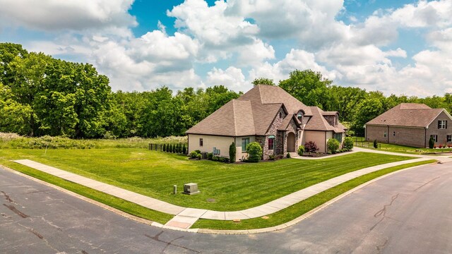 view of front facade featuring driveway, a front yard, and stone siding