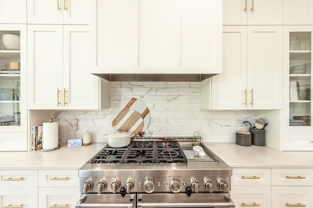 kitchen featuring high end range, white cabinets, light countertops, and backsplash