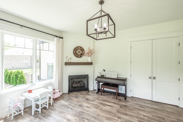 sitting room with a large fireplace, a chandelier, and wood finished floors