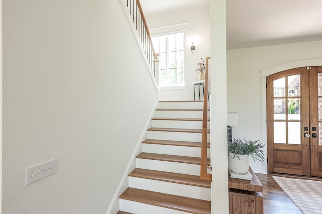 stairway with plenty of natural light, arched walkways, and wood finished floors