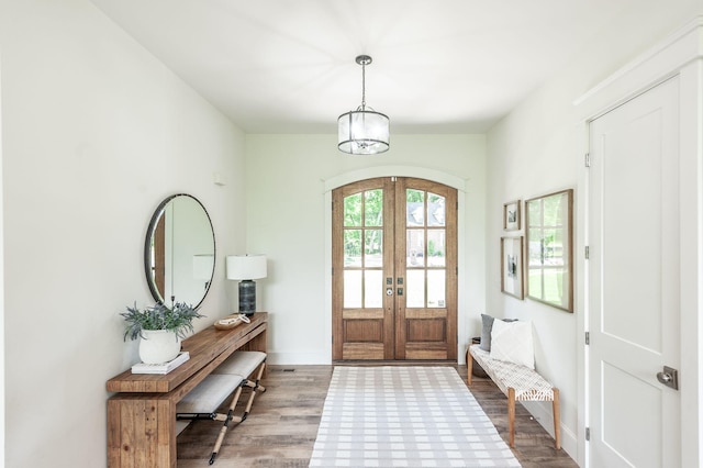 entrance foyer with french doors, wood finished floors, baseboards, and a chandelier