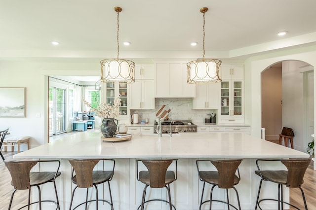 kitchen with arched walkways, white cabinetry, a spacious island, tasteful backsplash, and recessed lighting