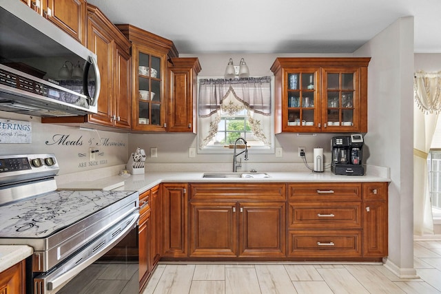 1172 Country Fields Ln, Clarksville, TN 37040 - kitchen with stainless steel appliances, a sink, brown cabinetry, light countertops, and glass insert cabinets