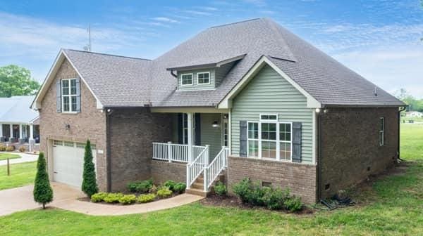 683 Northup Rd, Portland, TN 37148 - view of front of home featuring a garage, covered porch, brick siding, concrete driveway, and a front lawn
