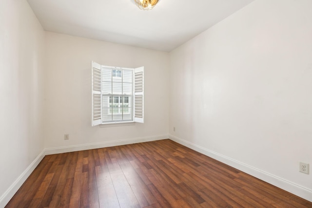 spare room featuring dark wood-type flooring and baseboards