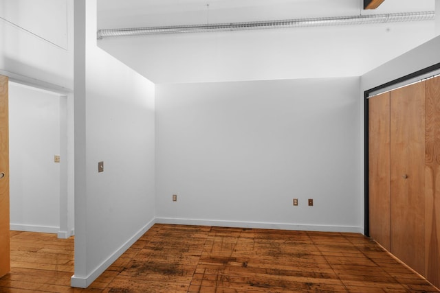 unfurnished bedroom featuring hardwood / wood-style flooring, a closet, and baseboards