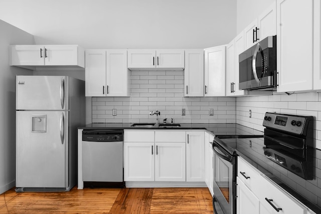 kitchen featuring stainless steel appliances, a sink, dark countertops, and white cabinets